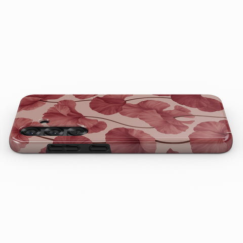 a phone case with a floral pattern of red leaves on a pink background.