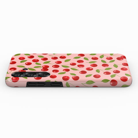 a pink phone case with a repeating pattern of red cherries and green leaves.