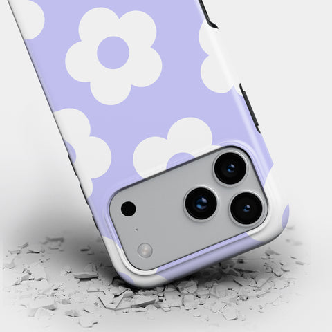 a smartphone case with a purple and white flower pattern, and it appears to be cracked or damaged, with pieces of the case scattered on the ground.
