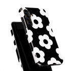 a black and white phone case with a repeating pattern of white flowers on a black background.