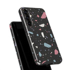 a black phone case with a colorful, abstract pattern of small, irregularly shaped tiles in various shades of pink, blue, and gray.